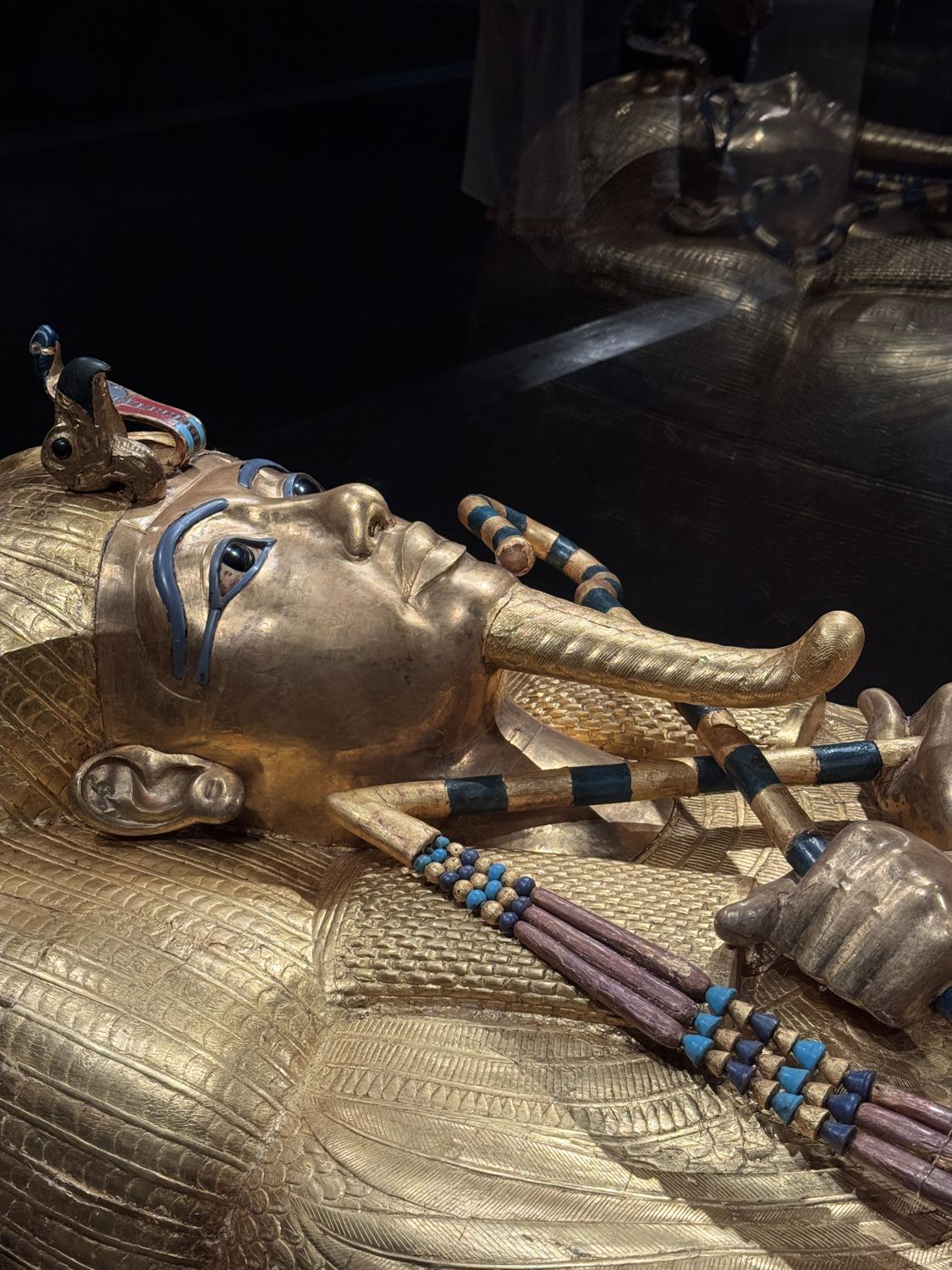 Close-up of Tutankhamun's golden coffin with inlaid eyes, crook and flail